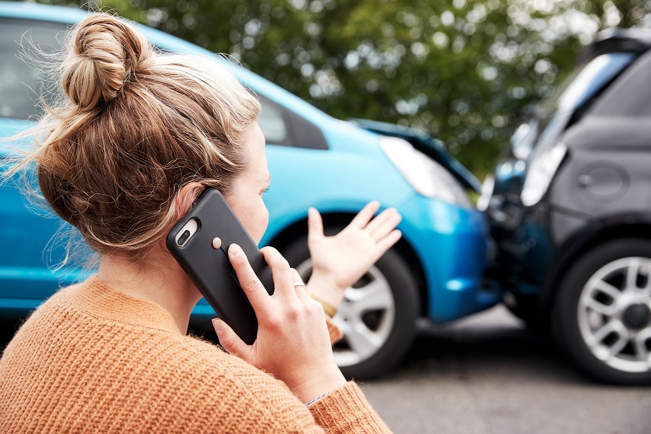 woman on phone at the scene of a car accident